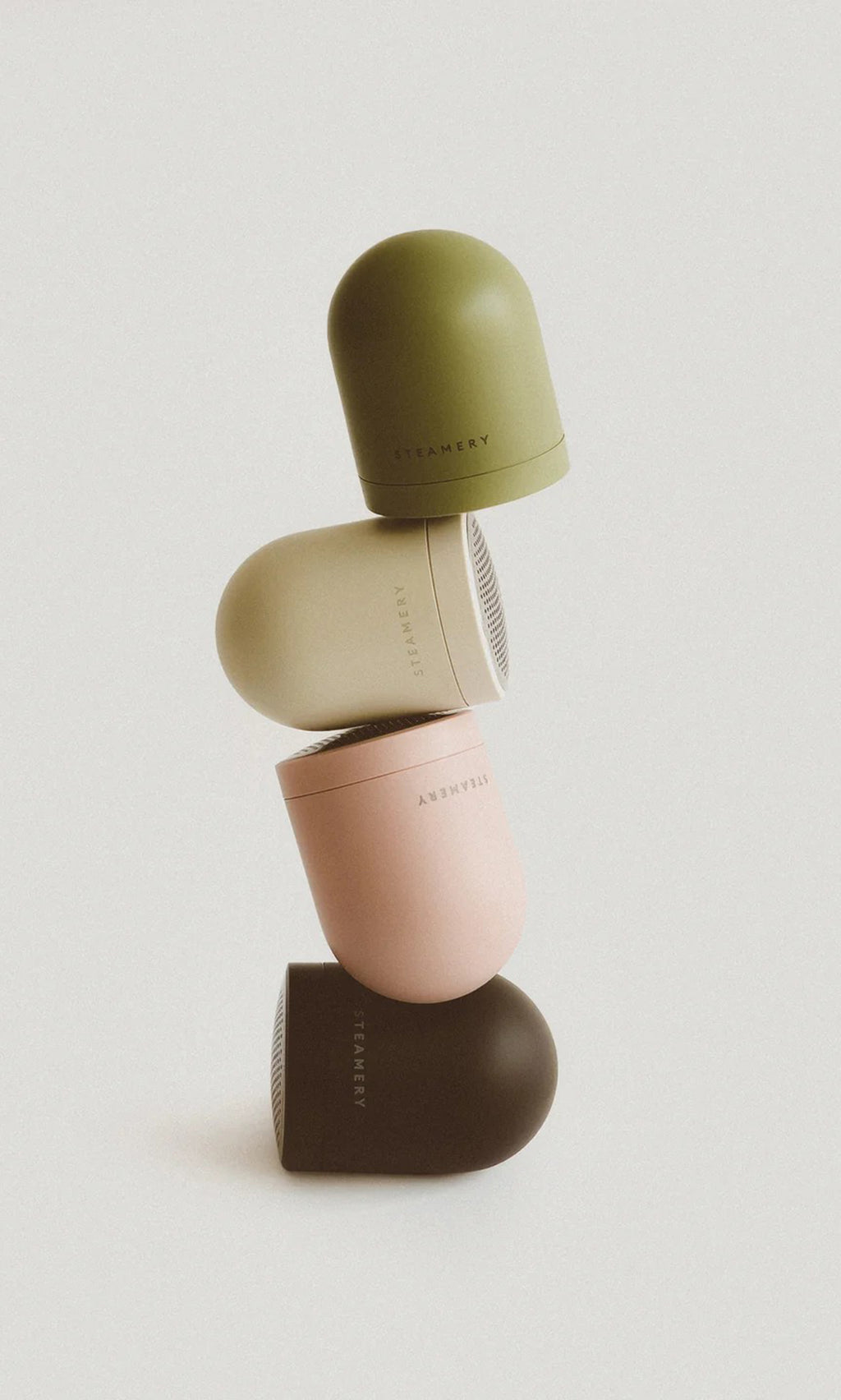 Plümo  Four Fabric Groomers in earthy hues are stacked vertically against a plain, light background.
